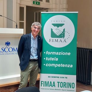 Uomo sorridente in posa davanti ad alcuni cartelloni