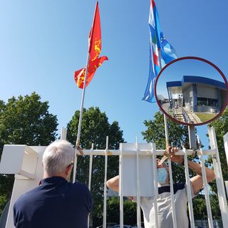 sindacalisti che montano bandiere su un cancello di azienda