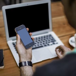 Uomo al pc con un cellulare in mano