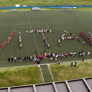 Persone schierate a formare una scritta su un campo di calcio