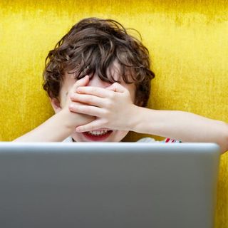 bambino si copre gli occhi di fronte a un computer