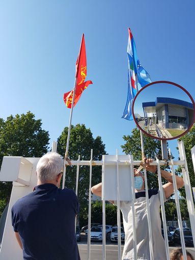 sindacalisti che montano bandiere su un cancello di azienda