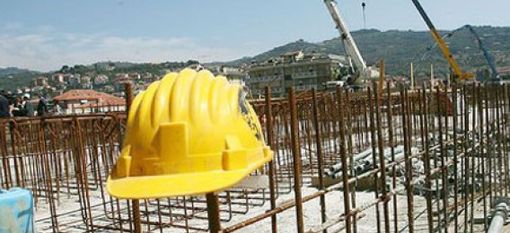 Cantieri fermi, con casco da operaio abbandonato in primo piano Cantieri fermi, con casco da operaio abbandonato in primo piano