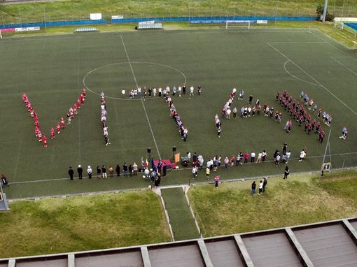 Persone schierate a formare una scritta su un campo di calcio