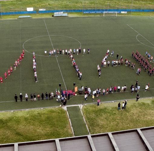 Persone schierate a formare una scritta su un campo di calcio