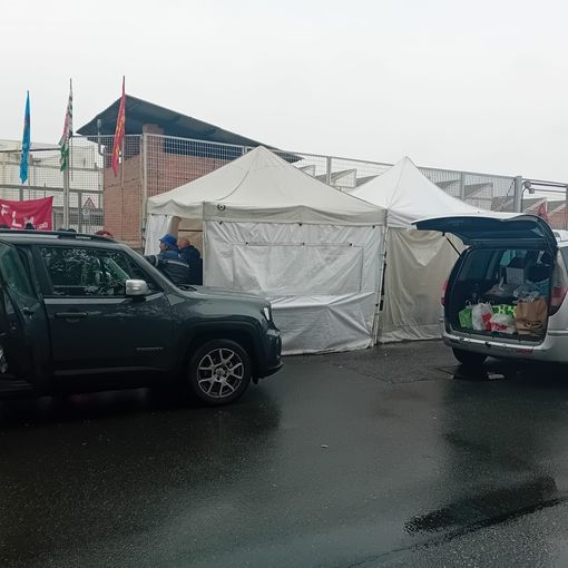 Persone insieme tra due auto con bagagliaio aperto