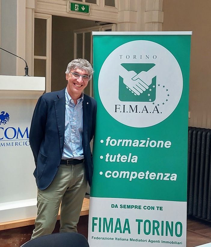 Uomo sorridente in posa davanti ad alcuni cartelloni