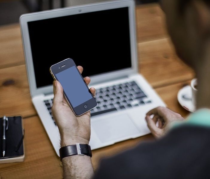 Uomo al pc con un cellulare in mano
