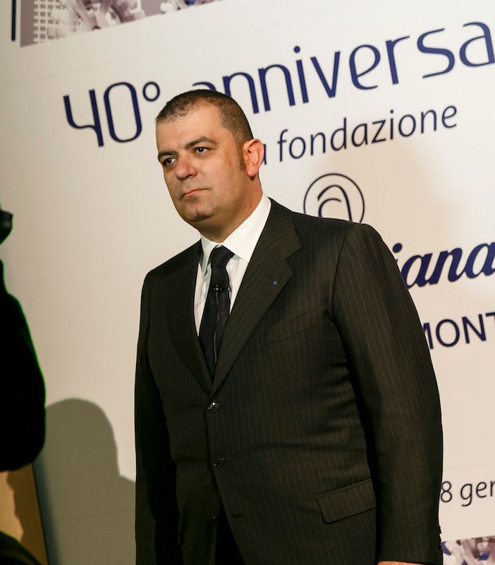 Uomo intervistato di fronte a pannello