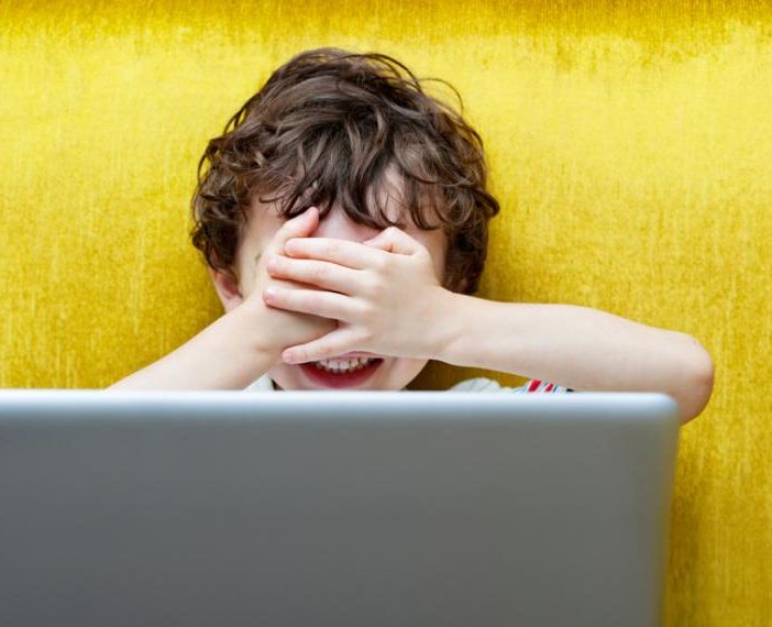 bambino si copre gli occhi di fronte a un computer