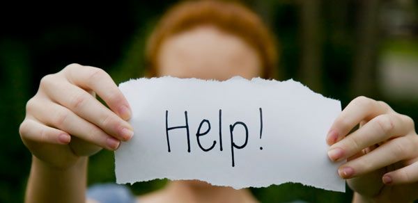 Ragazza tiene in mano cartello con la scritta &quot;help&quot;