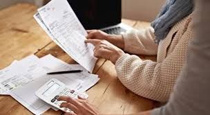 mani che sfogliano bollette e debiti