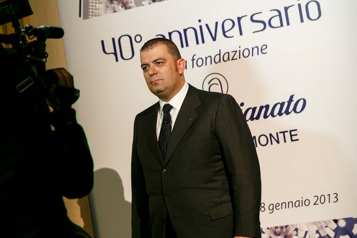 Uomo intervistato di fronte a pannello