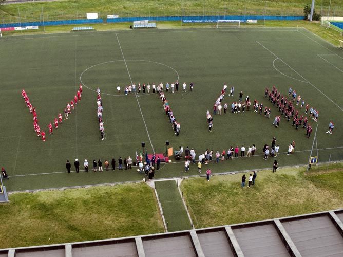 Persone schierate a formare una scritta su un campo di calcio