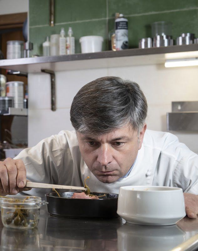 Cuoco che assaggia da una pentola con un cucchiaio di legno