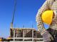 cantiere edile con uomo che tiene un caschetto sotto braccio