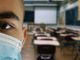 scuola con banchi e ragazzo in primo piano con la mascherina