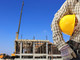 muratore con caschetto sotto il braccio e cantiere sullo sfondo muratore con caschetto sotto il braccio e cantiere sullo sfondo